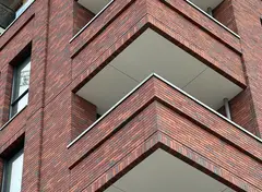 Bakstenen gebouw met balkons en lichte plafonds in de loggia’s.