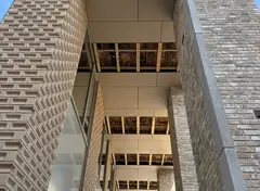 Overdekte doorgang met gevel van lichte baksteen tijdens montage van plafonds.