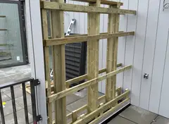 Houten onderconstructie voor gevel bij een gebouw met verticale panelen.