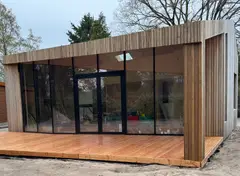 Modern huis met grote beglazing en verticale houten gevel.