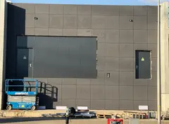 Donkere gevel van composietplaten met technische deur.