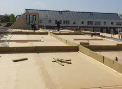 Bouwvakkers monteren dakelementen op een houten constructie.