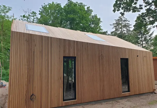 Modern huis met verticale houten gevel en twee dakramen.