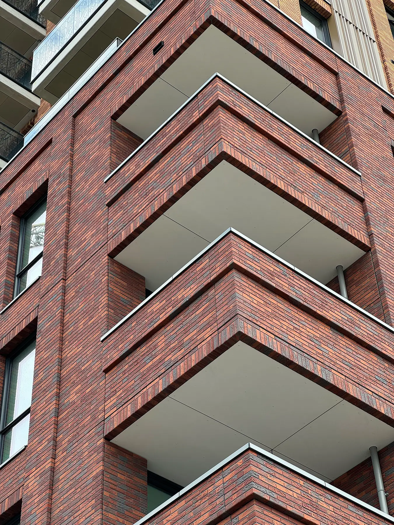 Bakstenen gebouw met balkons en lichte plafonds in de loggia’s.