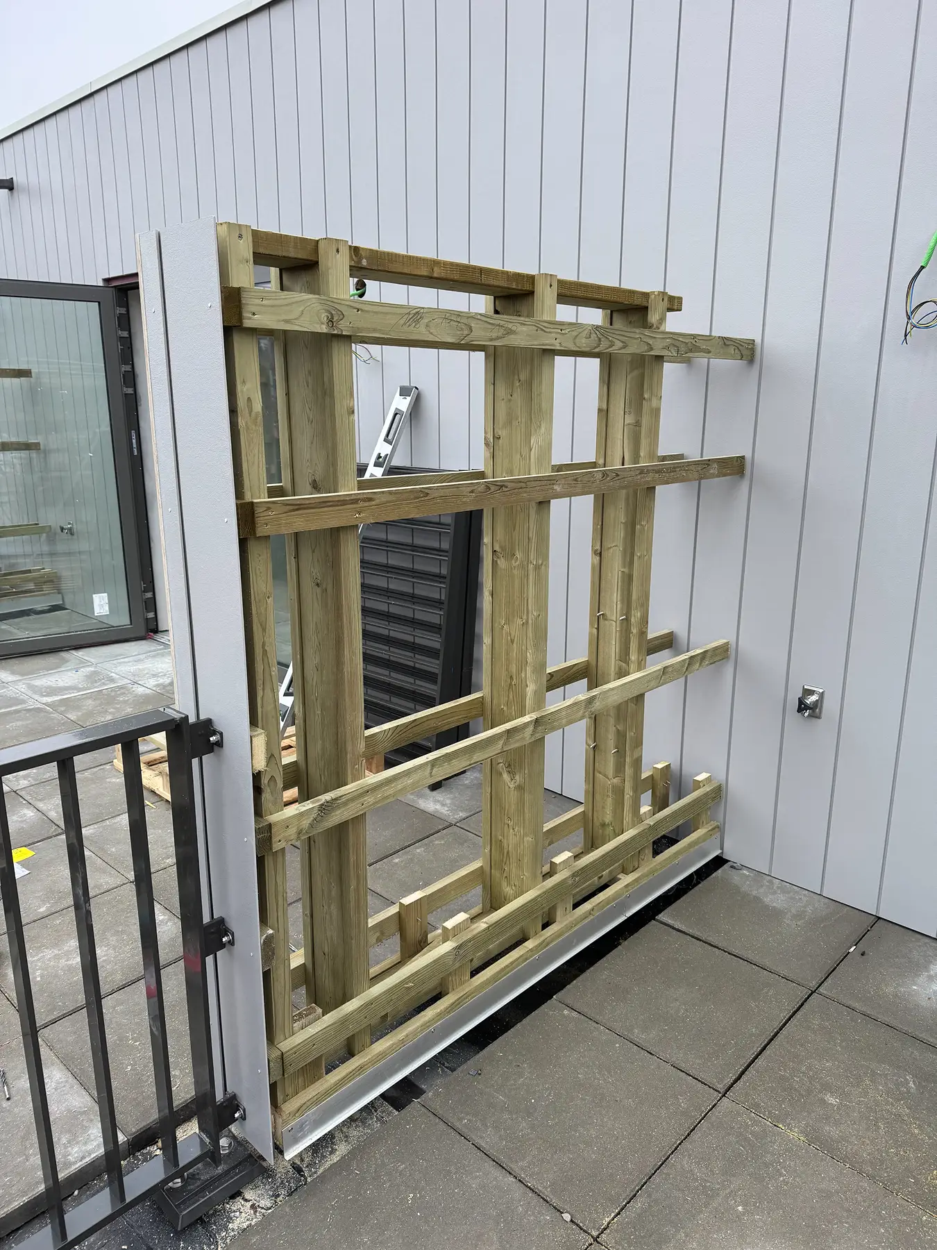 Houten onderconstructie voor gevel bij een gebouw met verticale panelen.