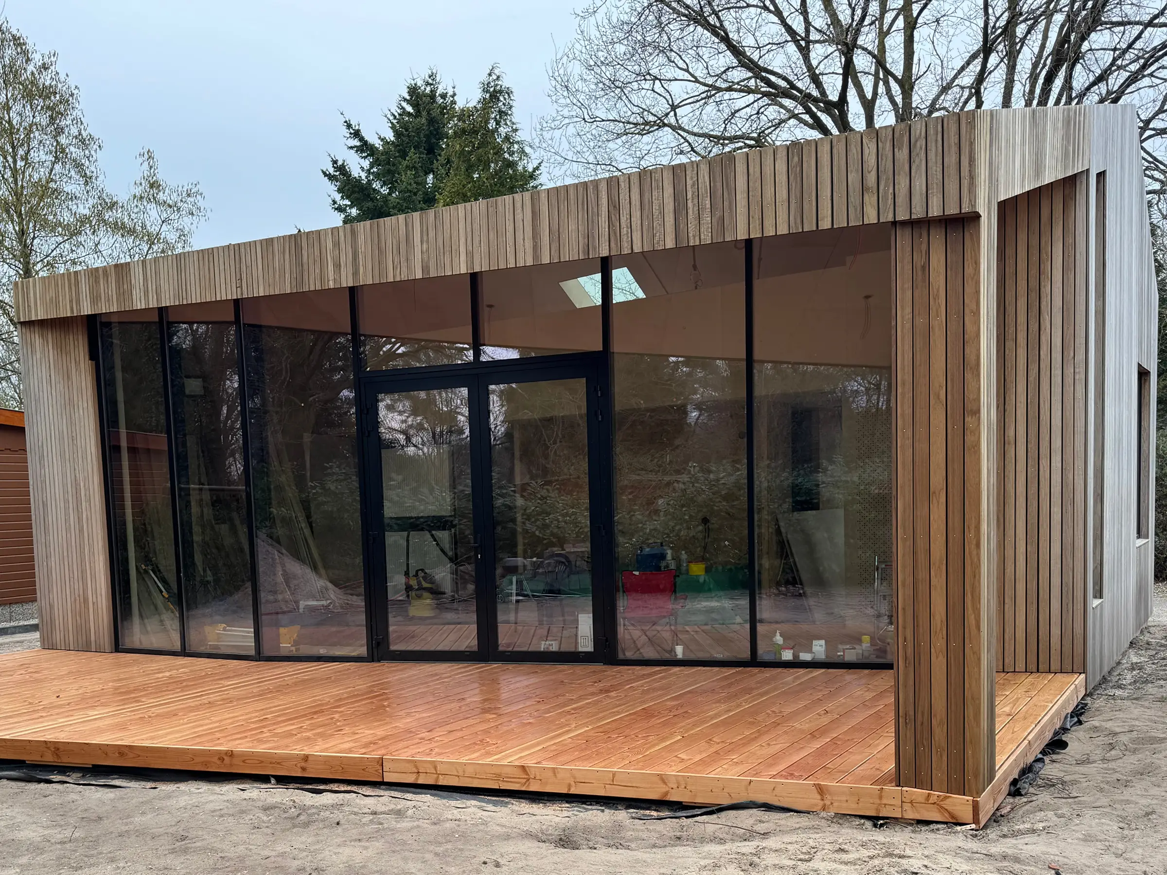 Modern huis met grote beglazing en verticale houten gevel.