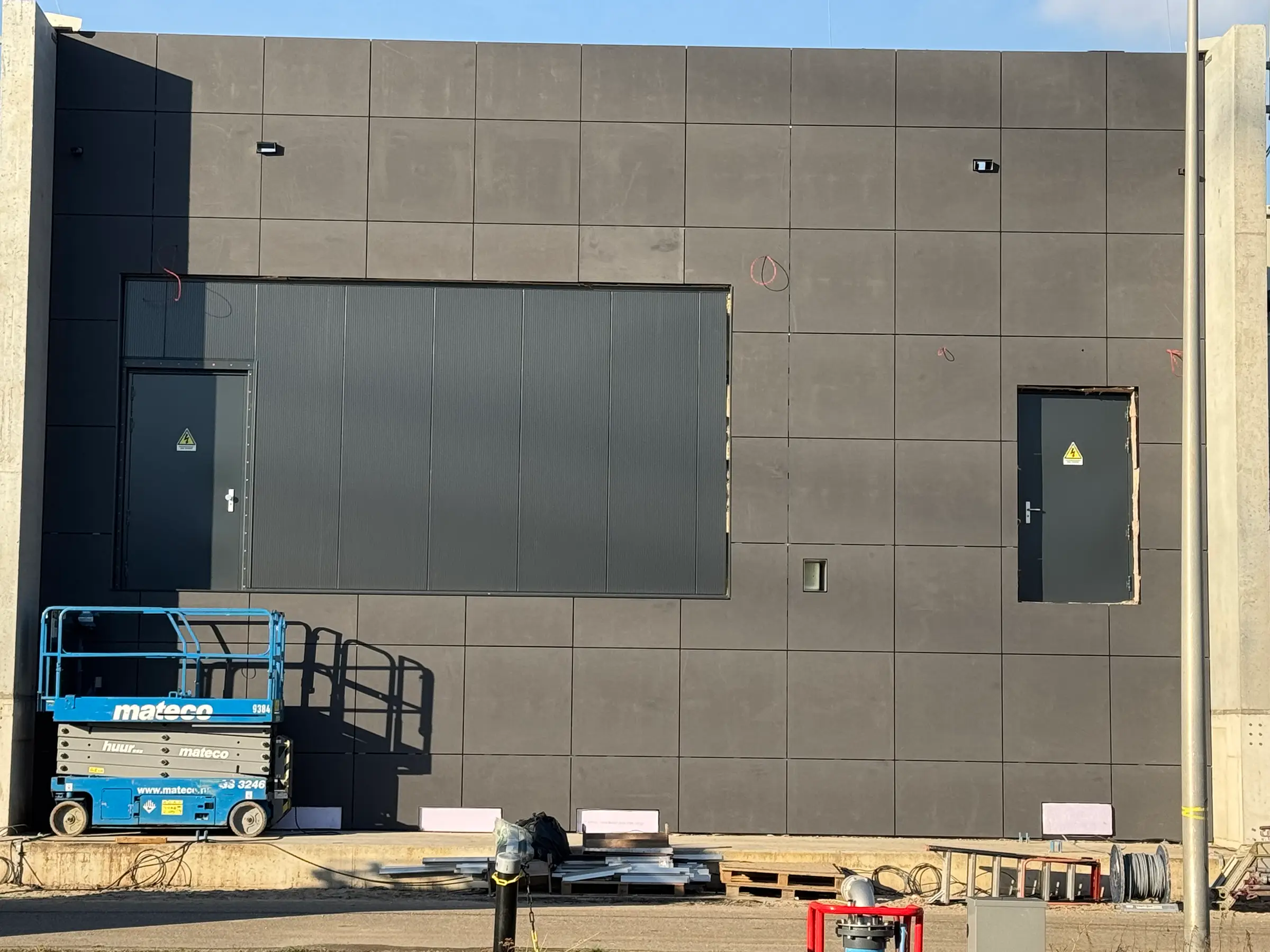 Donkere gevel van composietplaten met technische deur.