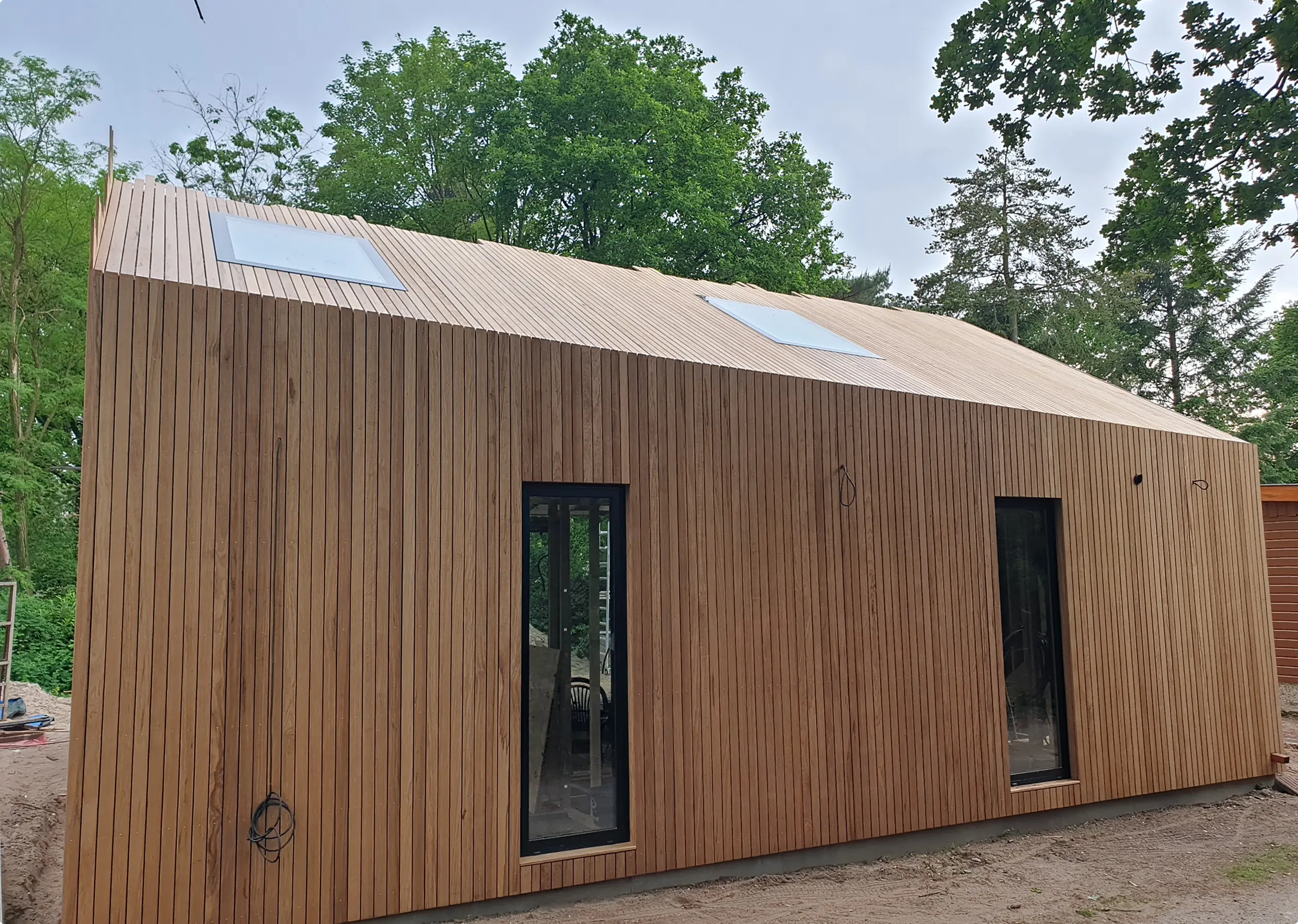 Modern huis met verticale houten gevel en twee dakramen.
