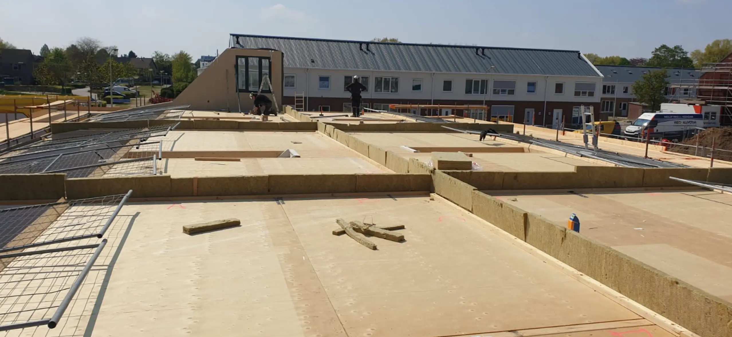 Bouwvakkers monteren dakelementen op een houten constructie.