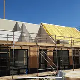 Een huis in aanbouw met steigerwerk en montage van een dak met isolatie.